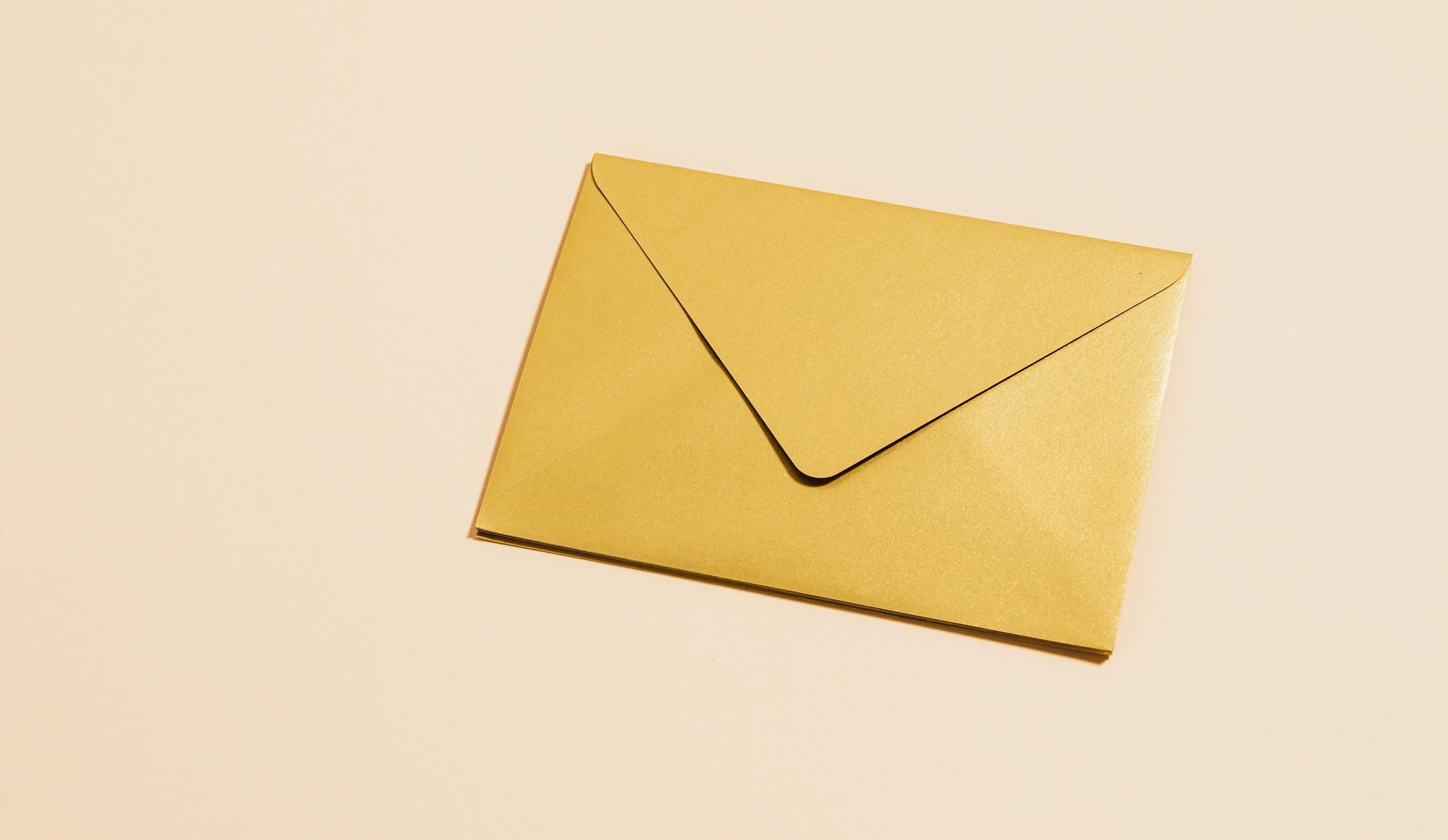 A sleek gold envelope placed on a vibrant yellow background, perfect for postal themes.